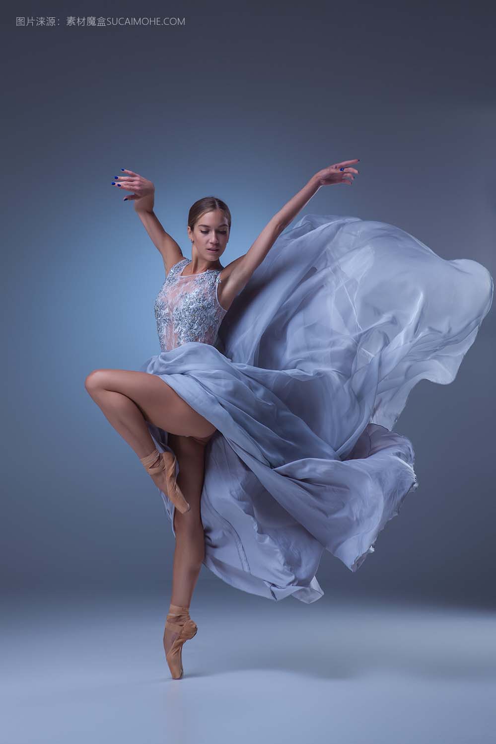 美丽的芭蕾舞演员在蓝色背景上的长长的蓝色裙子跳舞
