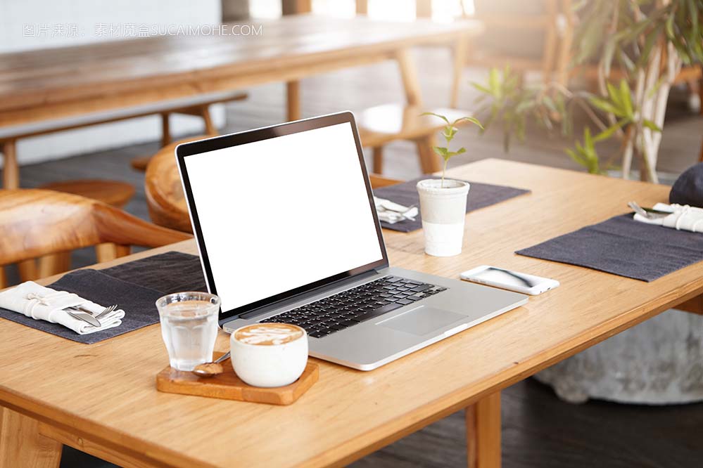 没人陪伴时未知的自由职业者的工作场所：一杯咖啡，一杯水，手机和通用笔记本电脑的简约
