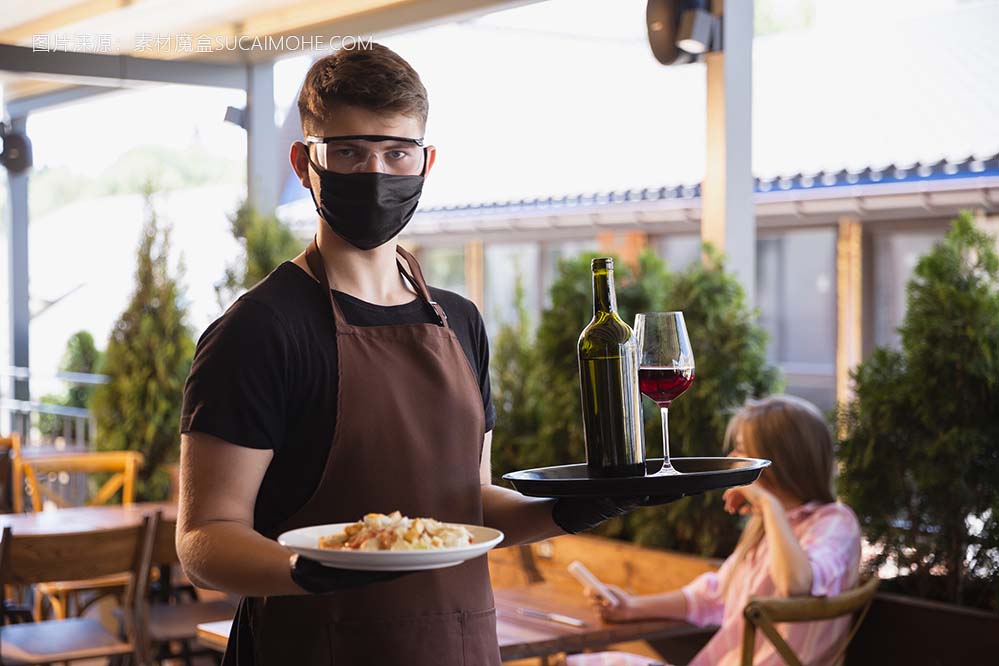 服务员在一家餐厅里戴着医用口罩，在冠状病毒大流行期间戴着手套照片