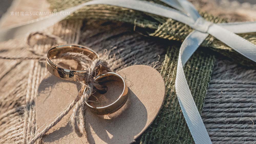 金色的结婚戒指，附在棕色心形纺织品上的特写镜头