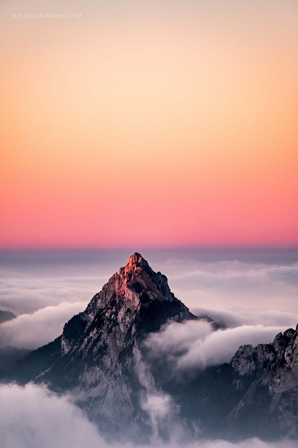 在美丽的粉红色的天空下的雾覆盖着一座山的鸟瞰图的照片