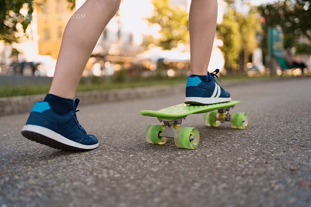 活跃的儿童户外运动。儿童滑板close-up-legs-blue-sneakers-riding-green-skateboard-motion-active-urban-lifesty