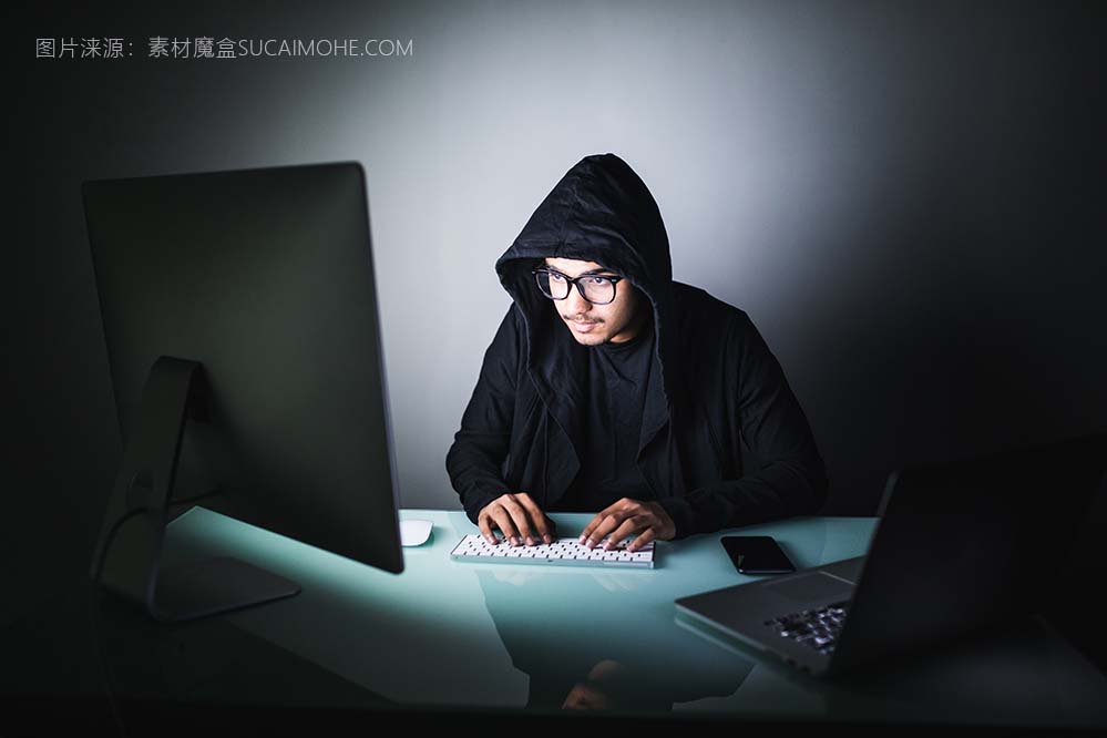 印度黑客深色帽衫坐在前面笔记本电脑隐私攻击