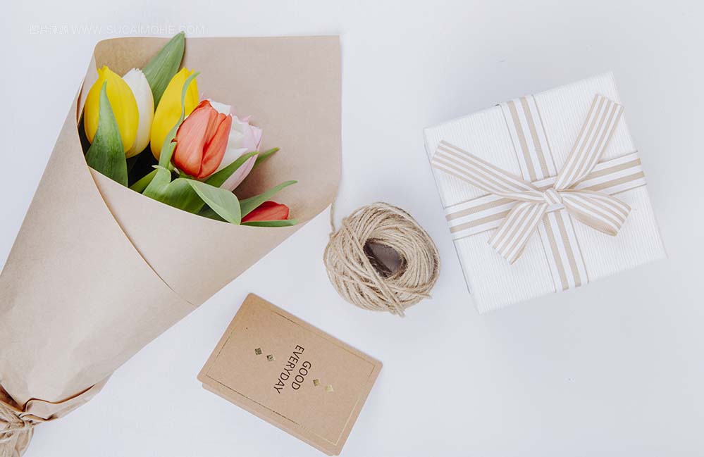 一束五颜六色的郁金香的顶视图在与明信片礼物盒和绳索的牛皮纸中在白色背景top-view-bouquet